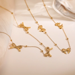 Elegant gold bow pendant necklace with bead chain on silk background