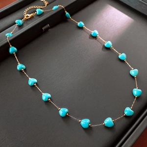 Close-up of gold chain necklace featuring multiple vibrant blue heart-shaped turquoise beads