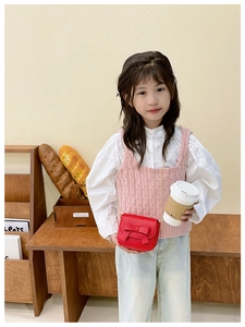 Girl wearing a mini red crossbody bag with bow detail over pink vest and white shirt