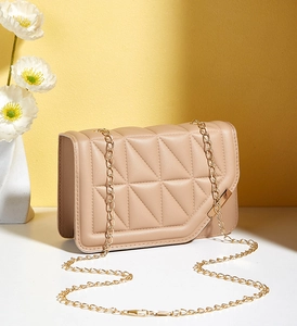 Detail of light brown crossbody bag with triangular texture and gold metal chain strap