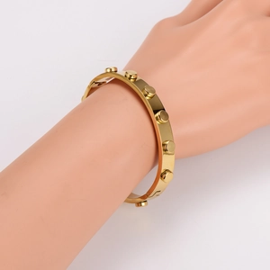 Punk style gold stainless steel rivet bangle displayed on arm with industrial design