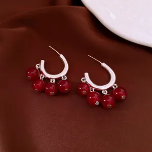 Vintage silver U-shaped earrings with dark red glass beads on silk background