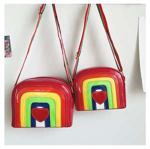 Close-up of rainbow crossbody bags in two sizes with red heart and striped straps