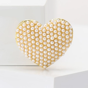 Detailed macro view of heart shaped brooch with white faux pearls on golden metal base