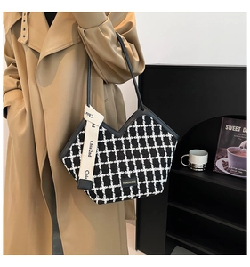 Detail of checkered tote bag with gold logo and decorative ribbon on khaki trench coat