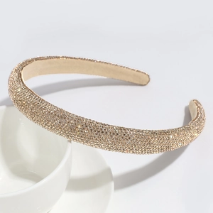 Close-up of luxury gold-tone headband with sparkling rhinestones on white ceramic