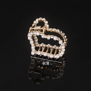 Detail of 4cm gold heart hair claw with pearls and rhinestones on black background