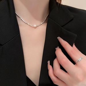 Silver geometric freshwater pearl necklace and wavy ring worn with a black blazer