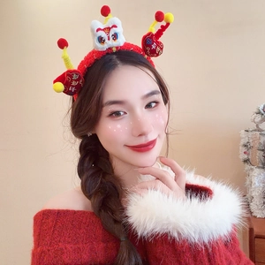 Detail of red plush festive headband featuring white lion dance head and yellow tassels