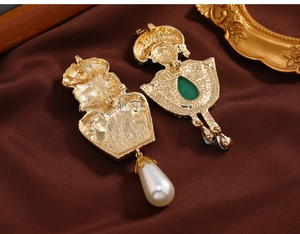 Macro view of vintage gold brooch pins showing back structure with pearl and emerald