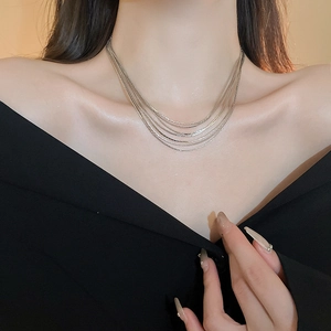 Nahaufnahme einer silbernen mehrlagigen Halskette an einem Modell mit Metalltexturen