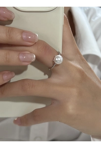 Elegante anello con perla in argento S925 indossato sulla mano con smartphone