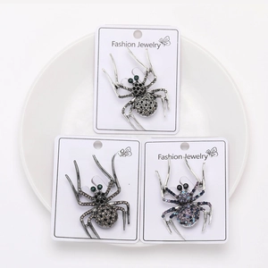 Detailed view of three vintage spider brooches with sparkling rhinestones on display card