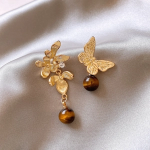 Vintage asymmetric gold flower earrings with tiger eye stones on grey silk fabric