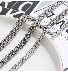 Detailed view of silver Byzantine chain necklace on a white ceramic display plate