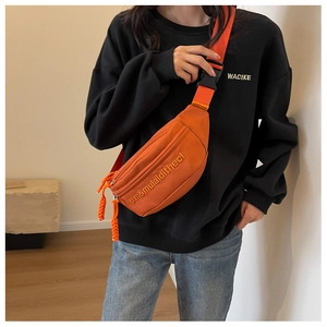 Close-up of orange canvas chest bag featuring embroidered text and adjustable strap