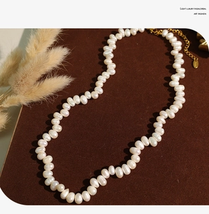 Close-up of natural irregular pearls necklace on brown velvet with golden extender