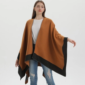 Full view of a stylish camel knit shawl with black trim on a model in a studio setting
