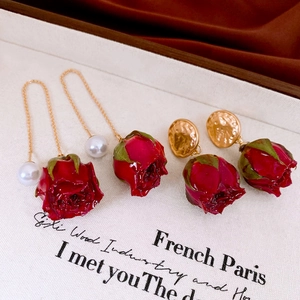 Detailed macro of vintage red rose earrings with pearls and gold accents in French style