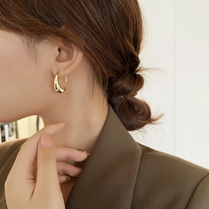 Close-up of minimalist 14k gold plated oval metal drop earring on model ear