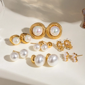 Set of seven vintage minimalist pearl earrings in gold-toned stainless steel on beige background