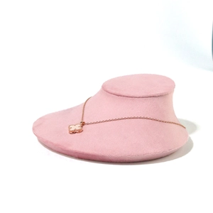Detail of rose gold clover necklace with white shell inlay on a pink velvet stand