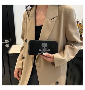 Close-up of black velvet clutch bag featuring sparkling rhinestone skull and crossbones