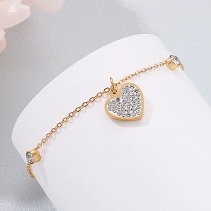 Close-up of golden heart bracelet with sparkling crystals on white display stand