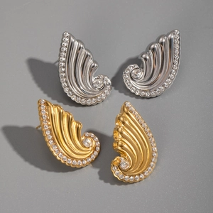 Detail view of wave-shaped wing stud earrings in gold and silver finish with crystals