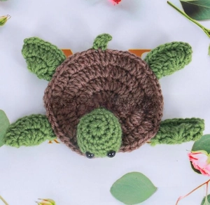 Macro shot of handcrafted crochet turtle coaster with green shell and spiraled textures