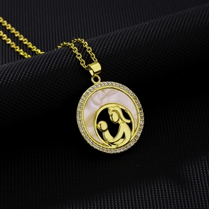 Macro detail of gold-plated mother and child pendant with shell inlay and zircon border