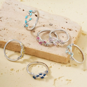 Leaf design ring set with colorful gemstones and diamonds on a beige stone base