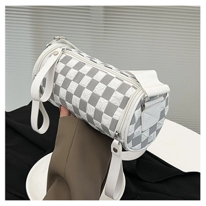 Close-up of a checkered cylinder bag featuring quilted nylon and a wide strap