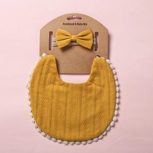 Détail d'un bavoir en coton gaufré jaune moutarde avec dentelle et bandeau assorti