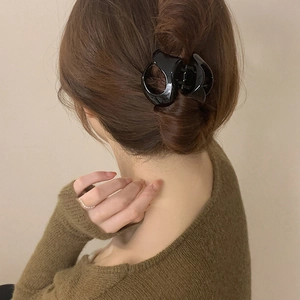 Side view of a woman wearing a large black glossy hair claw clip for a secure bun hairstyle