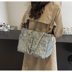 Gray-green floral corduroy shoulder bag shown on model in a cozy cafe setting
