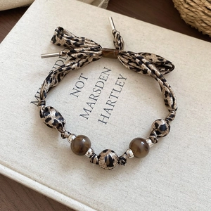 Détail du bracelet ethnique léopard en tissu avec perles sur un livre vintage
