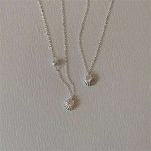 Close-up of shell pendant necklace with pearl detail on polished silver-tone metal chain