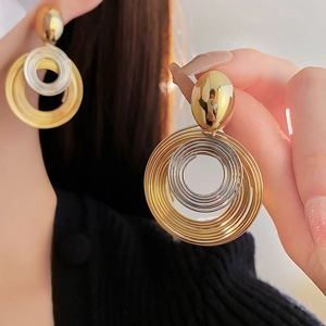 Detail of large multi-layer spiral hoop earrings in gold and silver metallic finish