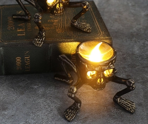 Gothic skull hands LED candle holder in dark bronze finish on a vintage book