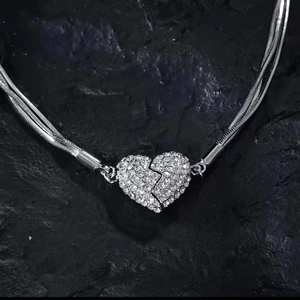 Multi-layer silver heart necklace with sparkling rhinestones on textured black stone surface