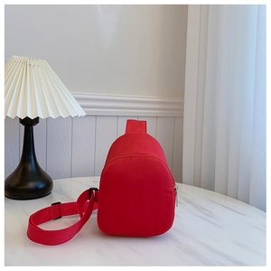 Close-up of a minimalist red nylon crossbody chest bag for kids on a marble surface