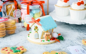 Macro detail of DIY 3D gingerbread house with icing and matching cartoon man cookie