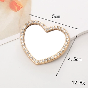 Detail view of heart-shaped gold mirror with inlaid rhinestones and 5cm x 4.5cm dimensions