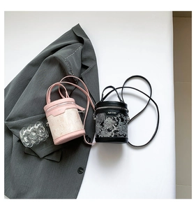 Detail of pink and black cylinder bags with intricate embroidery and metal hardware