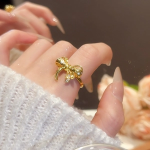 Detail shot of golden bow ring with micro-paved zircons worn on index finger