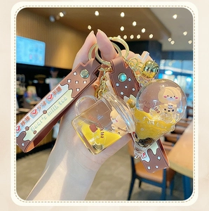 Detailed close-up of milk tea bear keychain with liquid floating bottle and gold bell