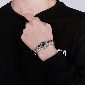 Close-up of vintage Cuban link bracelet with Freemasonry emblem on black hoodie