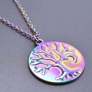 Macro shot of rainbow gradient tree of life and crescent moon pendant with steel chain