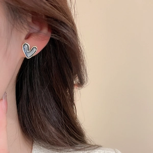 Close-up of heart-shaped pearl earrings featuring grey marble texture and gold borders